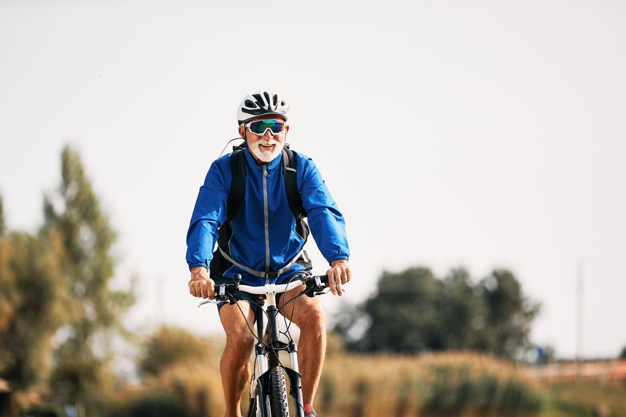 Happy senior athlete riding bicycle in nature.